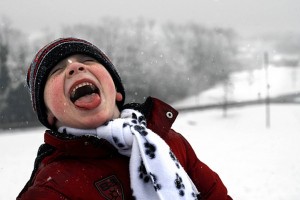 happy kid eating snow in the winter